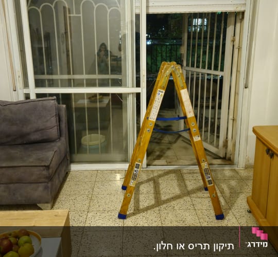 סולם עבודה מול חלון ותריס גלילה במהלך עבודת תיקון